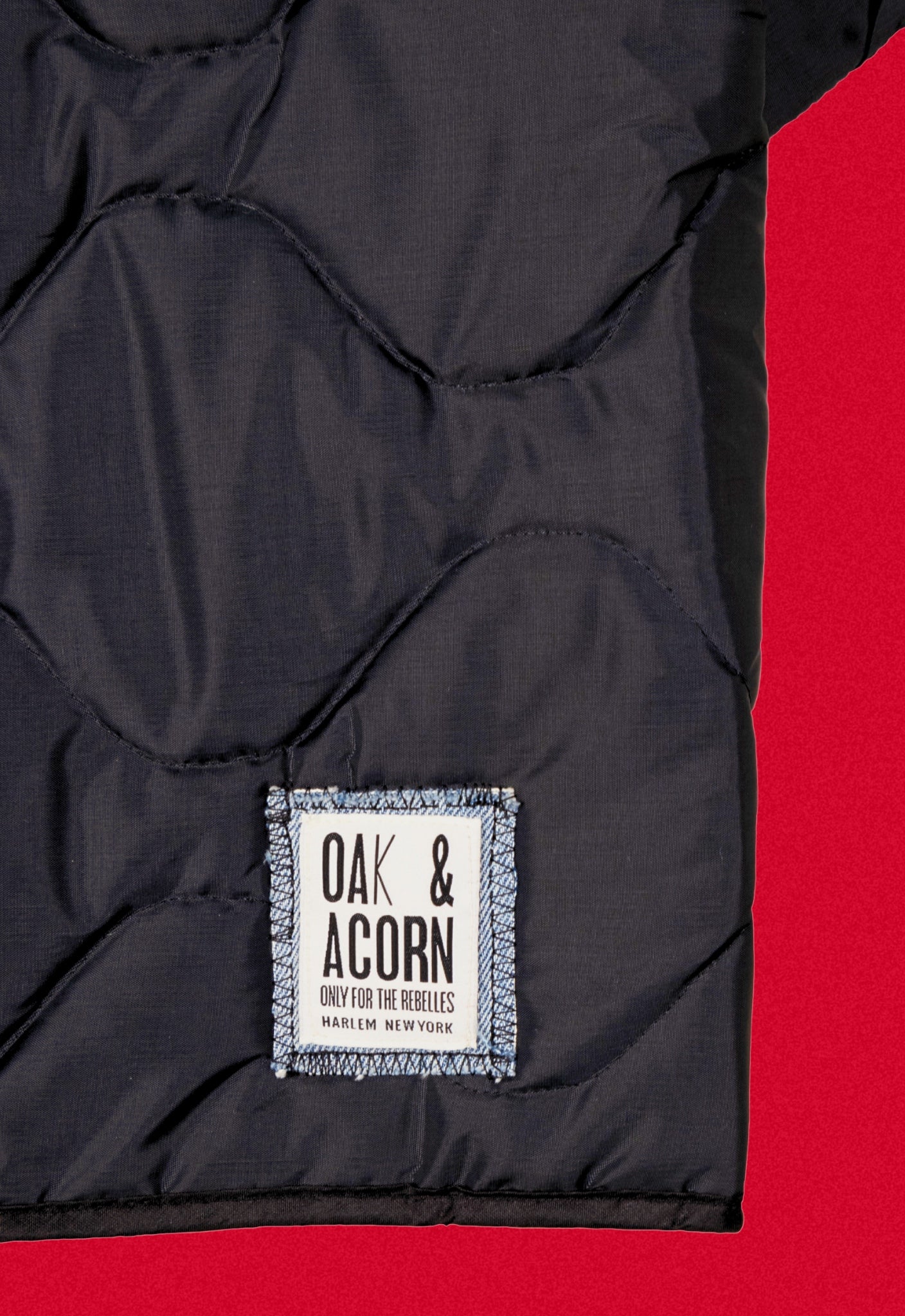 Black quilted repurposed denim jacket on a red background